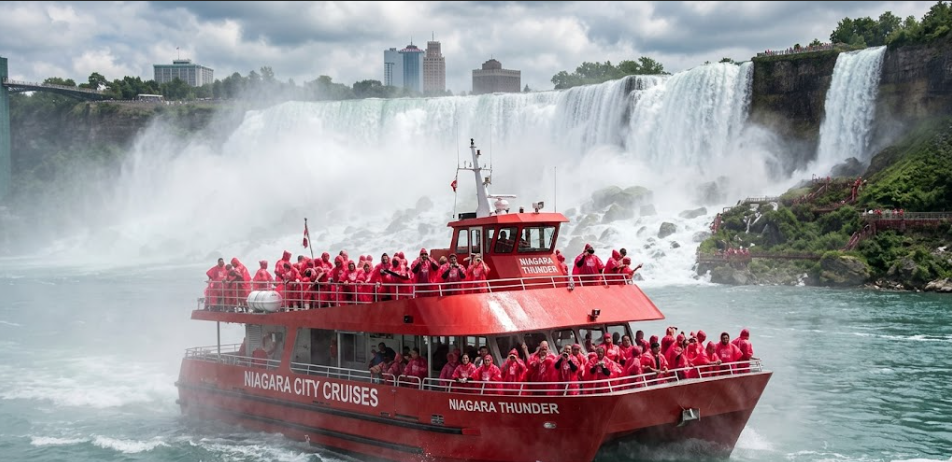 Niagara City Cruises catamaran vessel with passengers in red ponchos approaching Horseshoe Falls